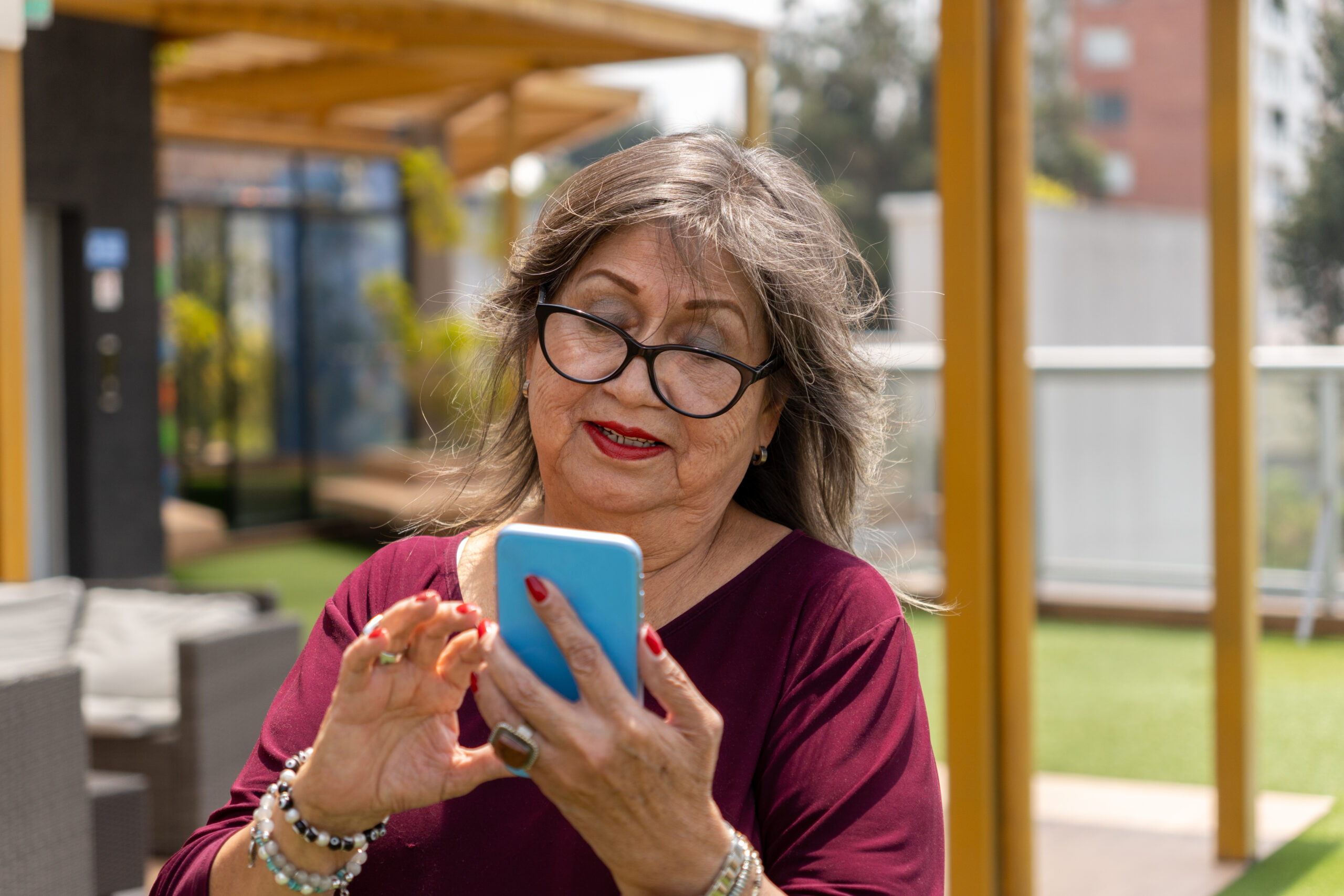 Portrait of a senior woman with glasses using her cell phone outdoors