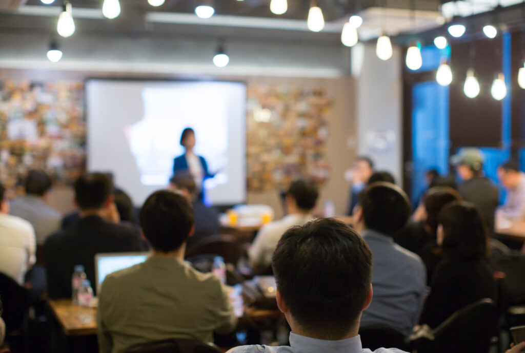 Audience Watching a Presentation. Defocused Blurred Presenter During Conference Meeting