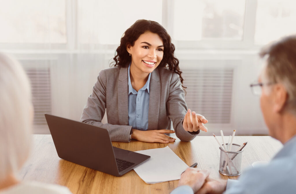 Expert. Senior couple sitting together at the desk and listening to their insurance financial advisor gesturing