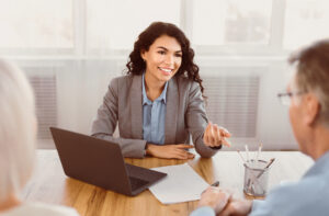 Expert. Senior couple sitting together at the desk and listening to their insurance financial advisor gesturing
