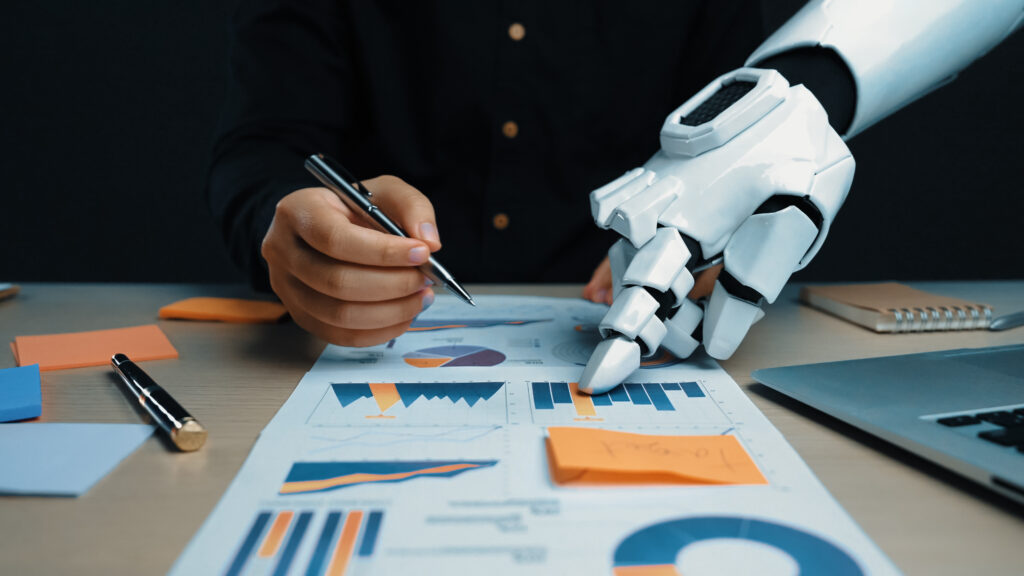 A unique scene depicting a robotic hand assisting a human in analyzing business charts and graphs, showcasing the future of technology and productivity in the workplace