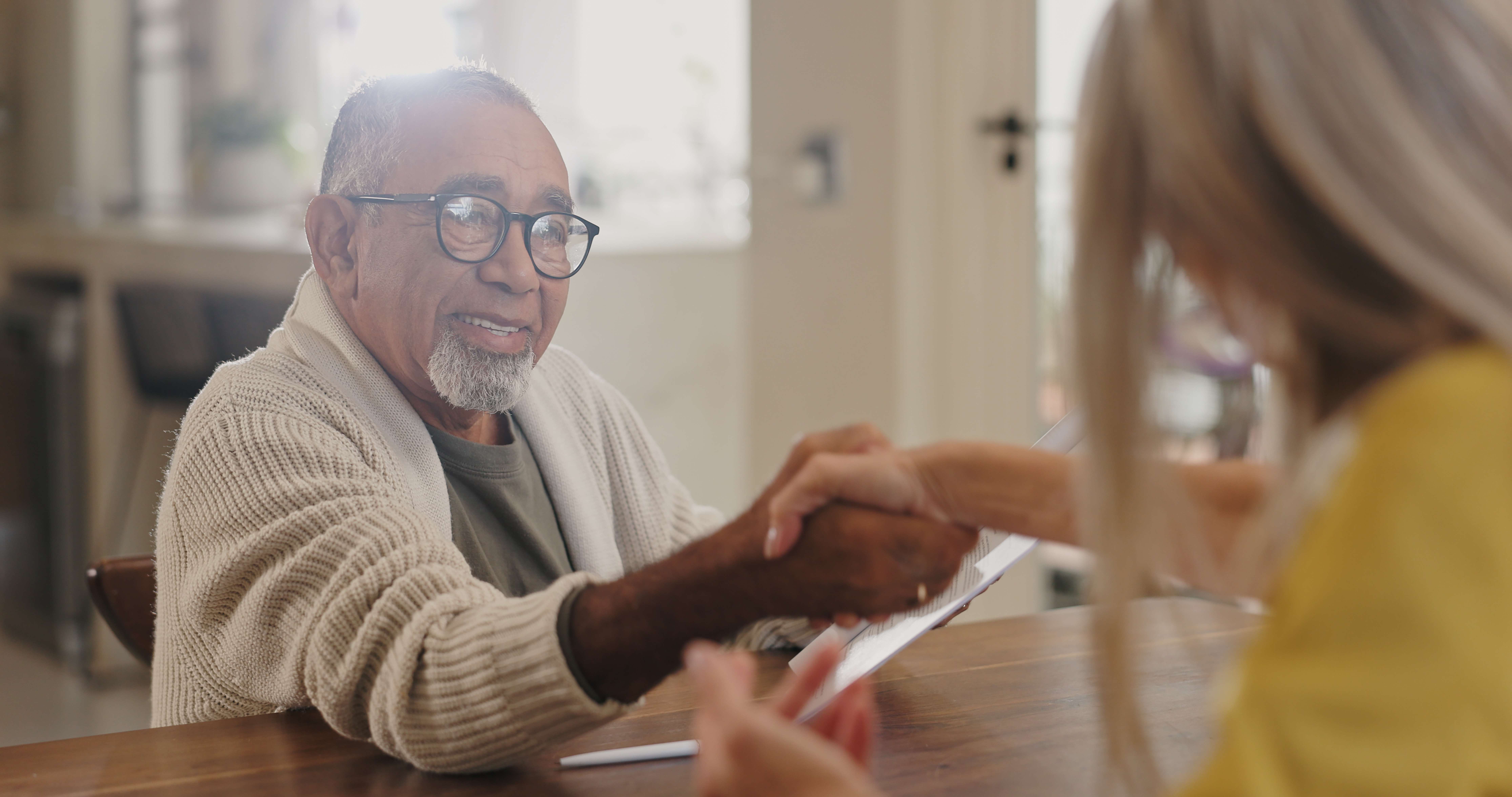 Senior man meeting insurance agent in home for advice or deal