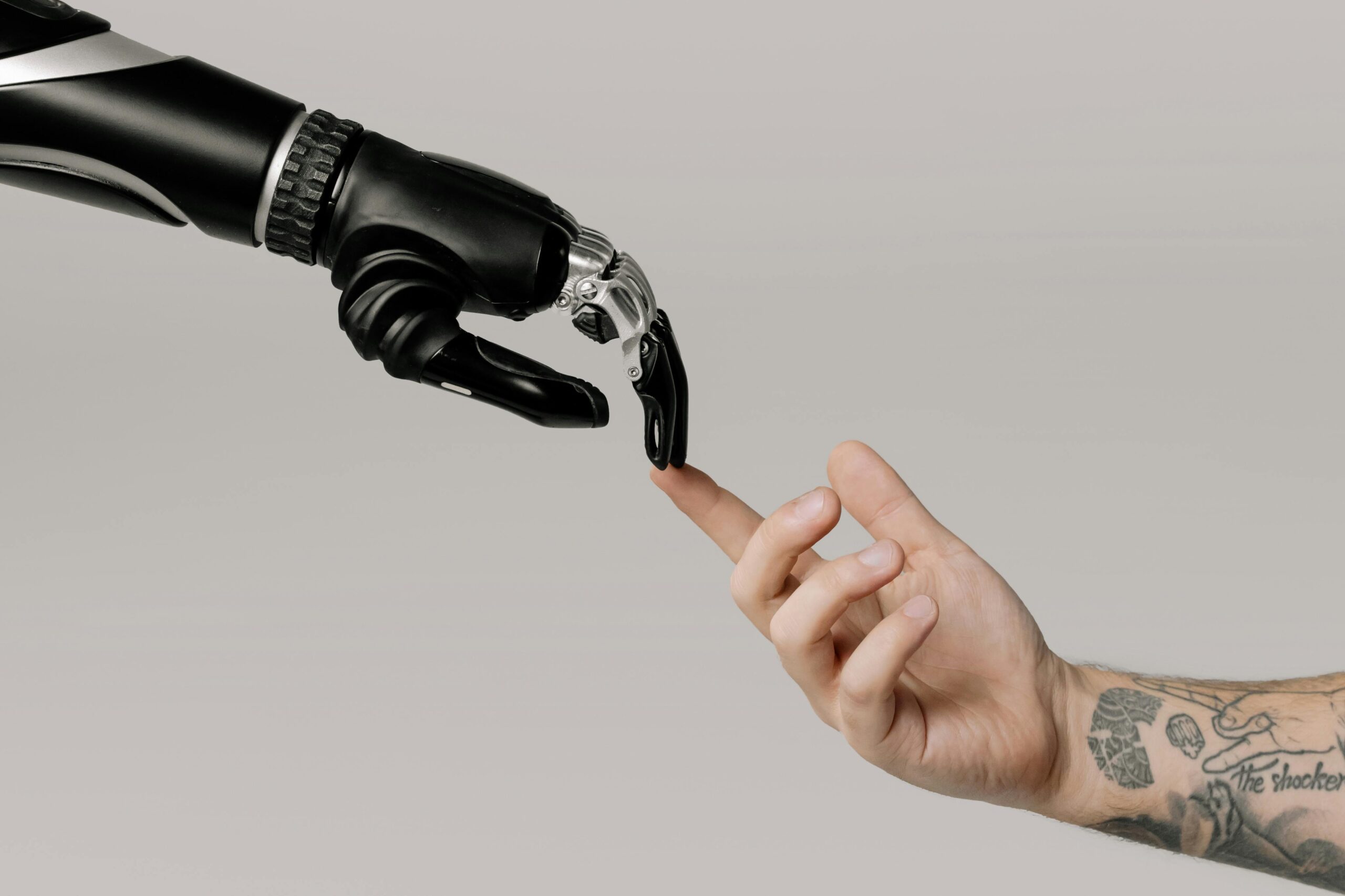 A human hand reaches for a robotic hand. Their fingers touch in the style of The Creation of Adam.