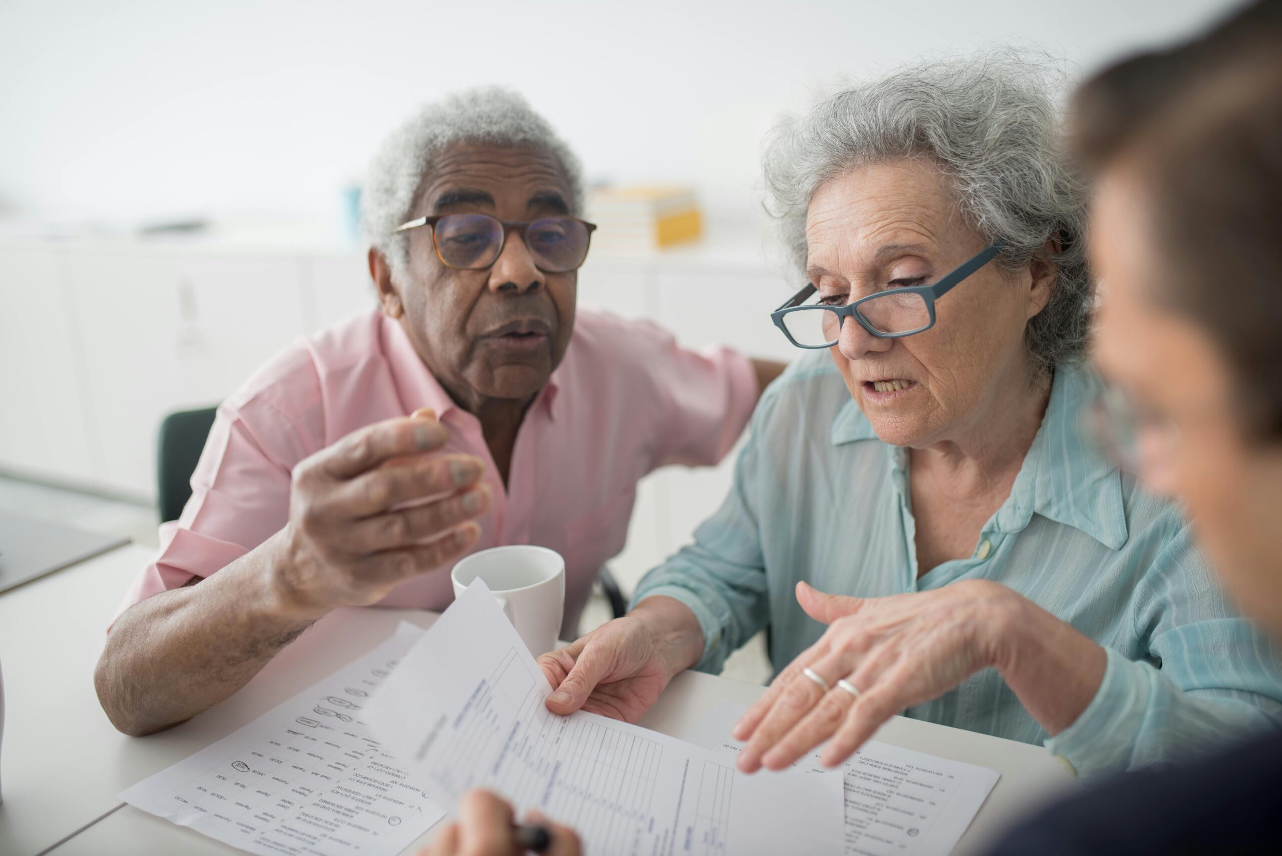 Senior couple reviewing insurance documents with an agent, discussing coverage options during a consultation.