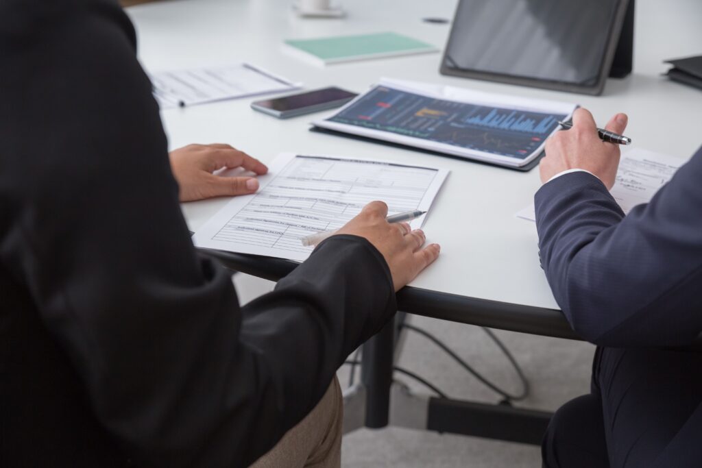 Two business professionals reviewing financial documents and data charts during a meeting.
