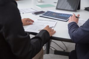 Two business professionals reviewing financial documents and data charts during a meeting.